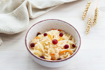 Pickled cabbage with cranberries in a bowl on a background of wheat. Russian traditional food.