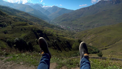 A young man is riding a swing in the mountains. First-person view of the Caucasus Mountains.