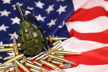 F1 frag grenade and many yellow bullets and cartridges on United States flag. Concept of gun...