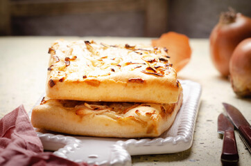 Italian focaccia bread with onions  on white ceramic tray.