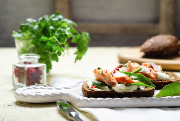 Healthy sandwich with rye bread with cream cheese, smoked salmon on wooden table.