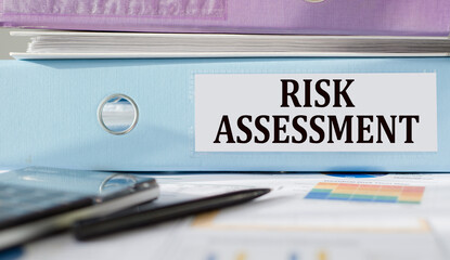 RISK ASSESSMENT text written on folder with documents and calculator.