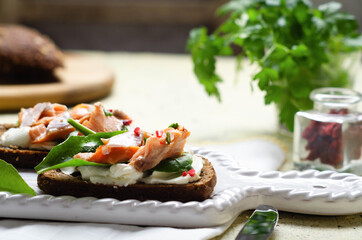 Healthy sandwich with rye bread with cream cheese, smoked salmon on wooden table.