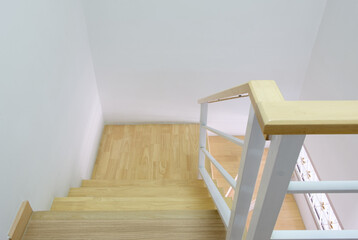 Modern curved wooden staircase with the white metal handrail.