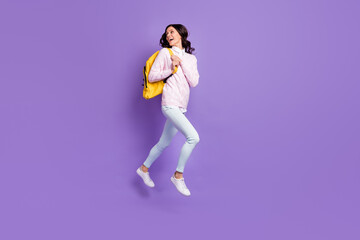 Fototapeta na wymiar Full length body size view of lovely cheerful glad wavy-haired girl jumping carrying backpack walking isolated on violet color background
