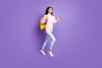 Fototapeta na wymiar Full length body size view of lovely cheery wavy-haired girl jumping carrying backpack going isolated on violet color background