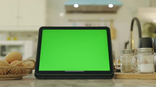 Tablet with green screen chroma key . In kitchen at home.