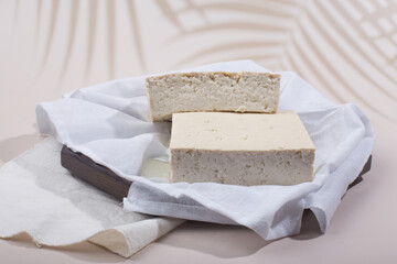 a block of two tofu in the cotton on the wood tray.