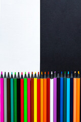 Close-up of colored pencils on a black and white background. Top view with copy space