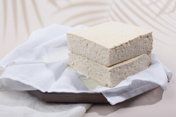 a block of two tofu in the cotton on the wood tray.