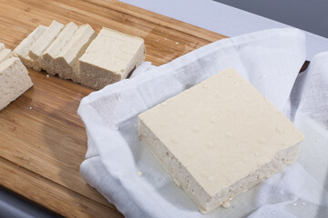 Slices of raw tofu on cutting board.