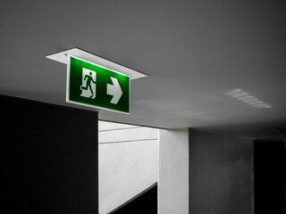 Green emergency exit sign hanging from ceiling.
