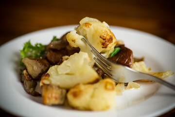 fried cauliflower with wild porcini mushrooms and onions in a plate