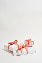 Vertical shot of a pile of gift boxes of different sizes with red bows on white background, web banner with copy space for text