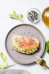 Avocado toast with salmon on white stone table background. Flat lay, top view