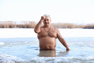 Fototapeta na wymiar Mature man immersing in river on winter day. Baptism ritual