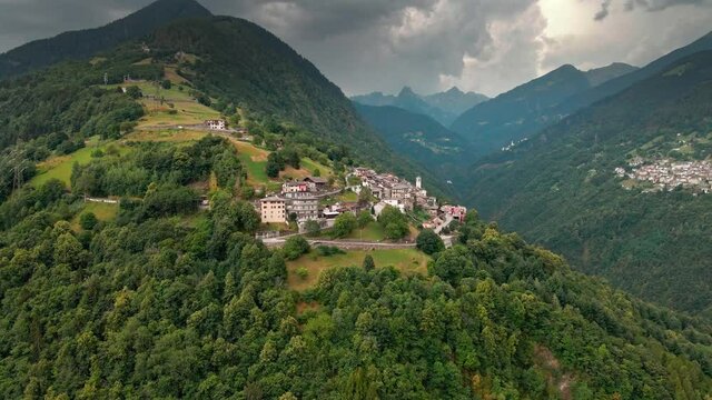Aerial View, Scenic Italian Orobie Alps, Green Forest, Mountain Peaks, Hillside Village Under Cloudy Stormy Sky, Drone Shot