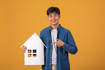 Fototapeta na wymiar Happy young man with a house shaped message bubble On orange background.