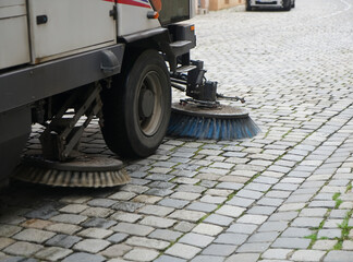 Street cleaner vehicle on the road collecting garbage and junk with brush rotation and vacuum...