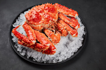 Boiled whole crab on ice over dark gray stone background