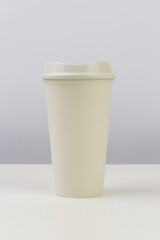 paper coffee cup mockup on white table with gray background. portrait orientation.