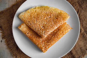 Pancakes on a white plate on a linen background. Russian traditional food crepes for the holiday Maslenitsa.