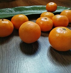 Tangerines on a wooden table against the background of a tropical leaf.