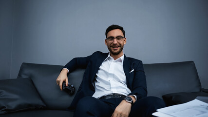 KYIV, UKRAINE - FEBRUARY 13, 2020: Happy businessman holding joystick near papers in hotel © LIGHTFIELD STUDIOS