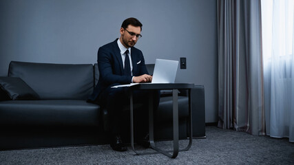 Businessman using laptop in modern hotel room
