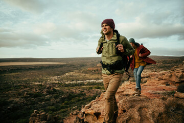 Caucasian male hiking holding backpack walking through mountain enjoying the fresh air