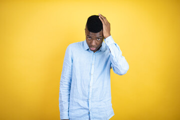 Young african american man wearing a casual shirt standing over yellow background putting one hand...