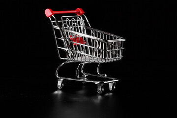 Empty metal grocery cart on a black background.