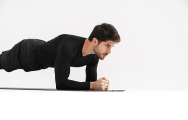 Young athletic sportsman doing exercise while working out on mat