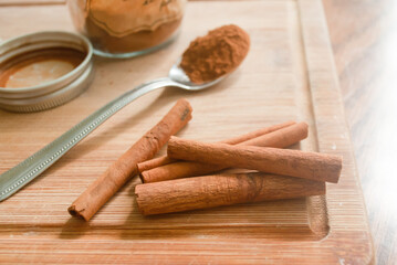 cinnamon sticks on a wooden board and a cinnamon power in a spoon 