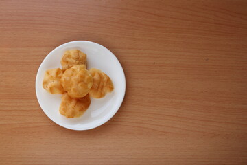 Top view round shape choux cream on round white dish  and light brown wood background.