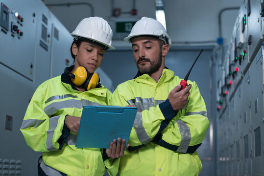 two workers in electrical control room.
