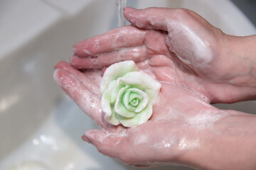 Fototapeta premium Human hands with rose-shaped handmade soap foam.
