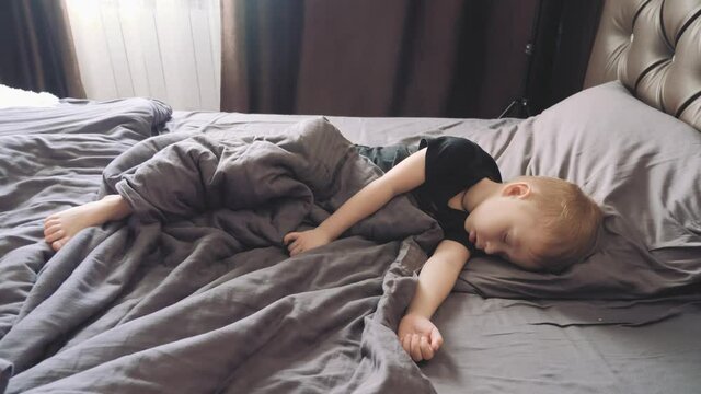 Peaceful baby boy lying on a bed while sleeping. Family, motherhood, love, health and care concept.