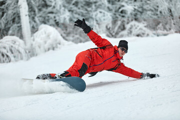 Male snowboarder in a red suit rides on the snowy hill with snowboard, Skiing and snowboarding...