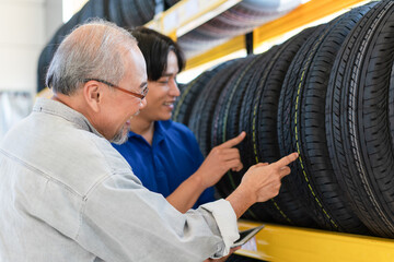 Asian senior customer man choosing wheel tires with man salesman at auto store shop and car repair...