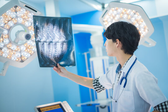 doctor looking at radiological spinal x-ray film for medical diagnosis on patient’s health on spine disease, bone cancer illness, spinal muscular atrophy, medical healthcare concept
