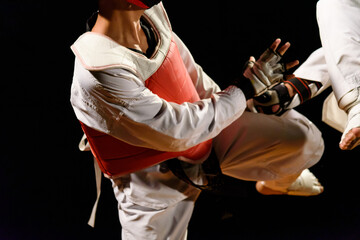 A taekwondo player is using his legs to kick his opponent. isolated on black  background.