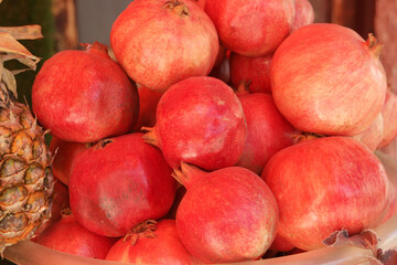 Heap of pomegranate fruits on market display. Fresh red pomegranates pile close up. Fruits at food market.