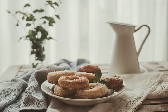 Plate of homemade donuts on a table by a window