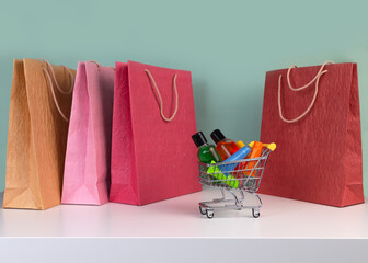 Colorful shopping packets and miniature shopping trolley cart with a set of cosmetics. World consumer day concept. Buying cosmetic, online shopping concept.Copy space.