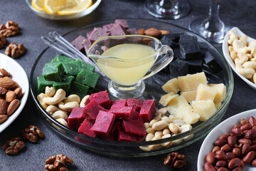 Multicolored gourmet cheese, olives, nuts, honey and sliced lemon on dark background. Appetizer for a wine party. Close-up