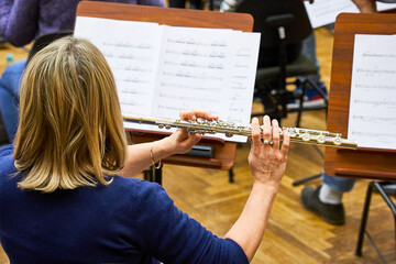 A woman plays the flute in a big symphony orchestra. A man plays fly. Rehearsal.