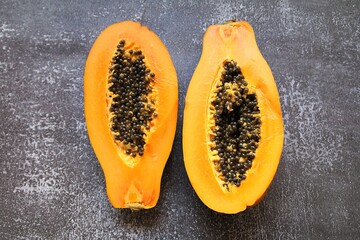 halved papaya, orange fruit with tiny seeds inside, juicy papaya with seeds, small seeds, fruit full of vitamins, healthy and natural food