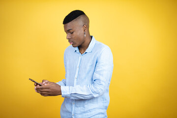 Young african american man wearing a casual shirt standing over yellow background chatting on the phone