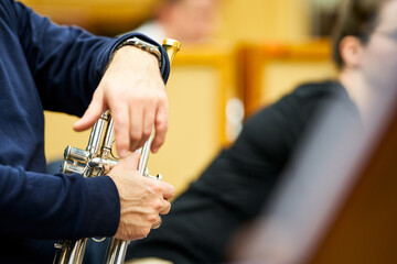 Trumpeter's hands resting on the trumpet during a break in the rehearsal.